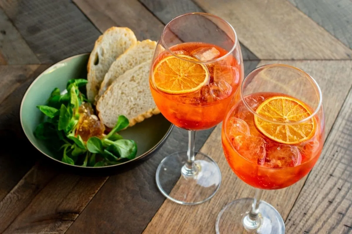 Ein Glas Aperol Spritz mit Eiswürfeln und einer Orangenscheibe.