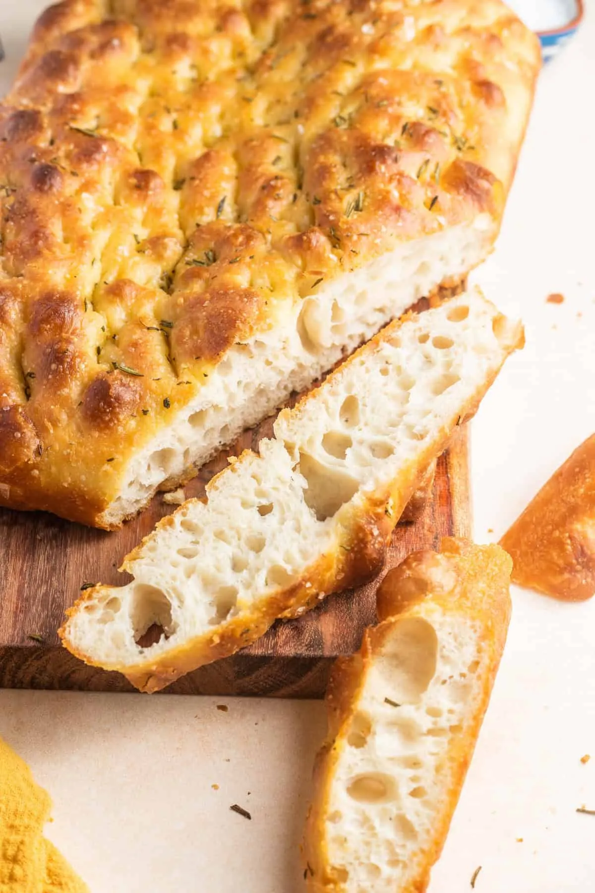 Ein großes Stück Focaccia, angeschnitten, auf einem Schneidebrett.