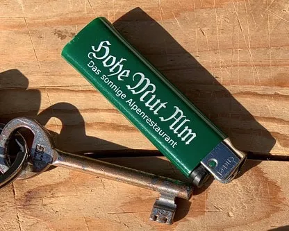 Ein Imker erwärmt vorsichtig einen Metallschlüssel mit einem Feuerzeug, um ihn als alternative Wärmequelle zur Behandlung eines Bienenstichs zu verwenden