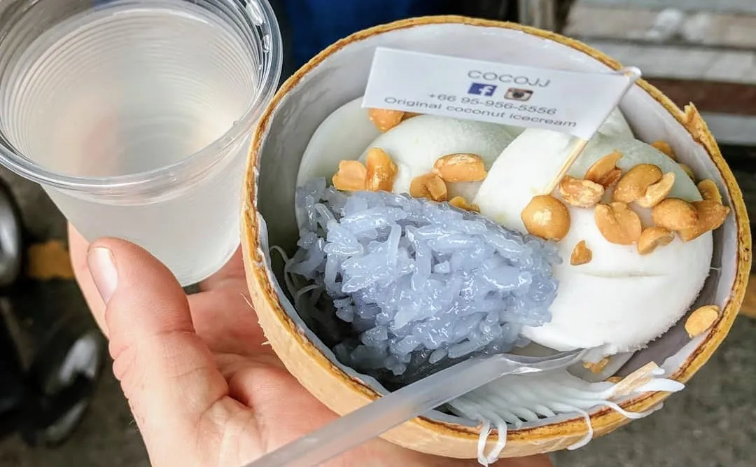 Ein Kokoseis mit klebrigem Reis und Erdnüssen, serviert in einer Kokosnussschale