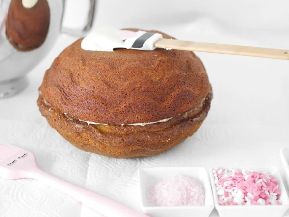 Ein Kuchen wird mit einer dicken Schicht cremigen Frischkäse-Frostings überzogen, das gleichmäßig verteilt wird.