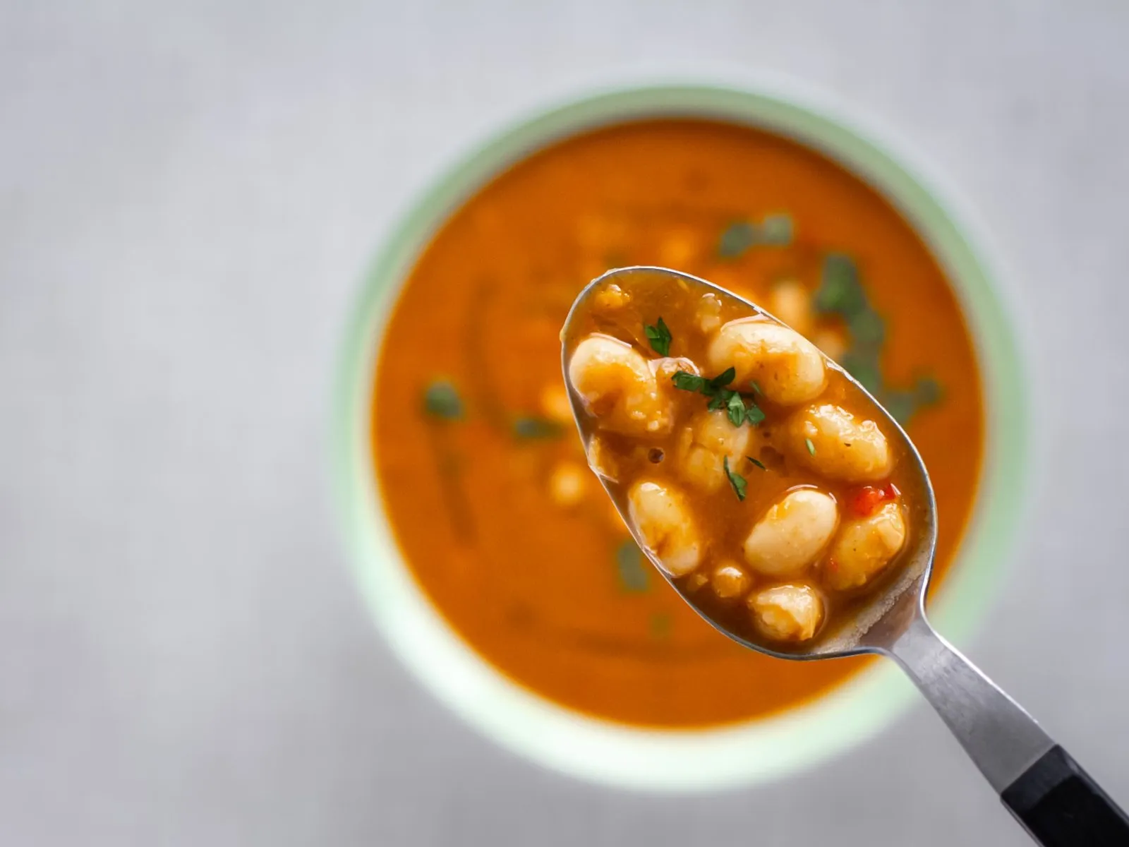 Ein Löffel gefüllt mit einer veganen weißen Bohnensuppe.
