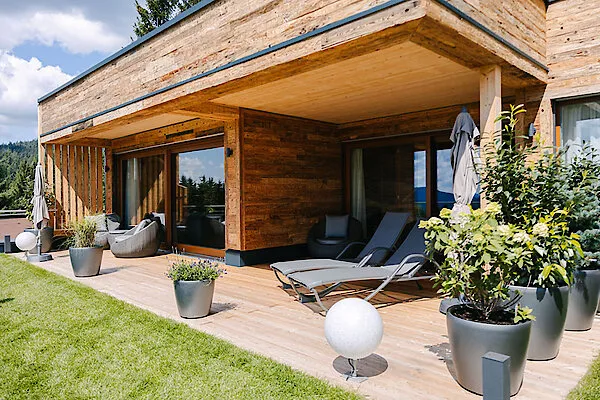 Ein luxuriöses Chalet im winterlichen Bayerischen Wald, umgeben von verschneiten Bäumen.