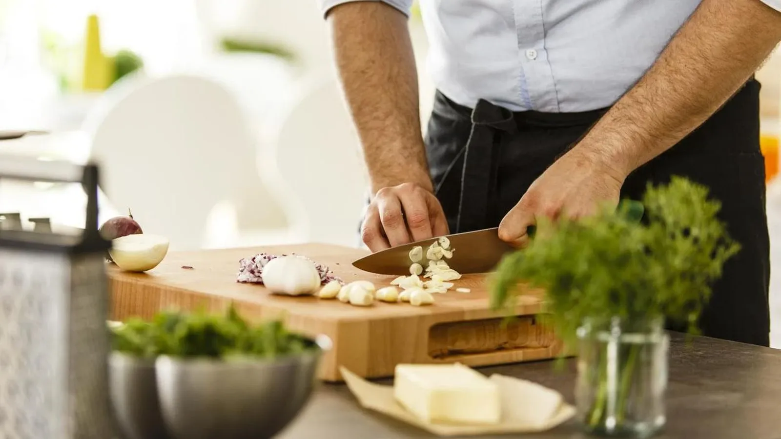 Ein Mann schneidet Knoblauch auf einem Holzbrett