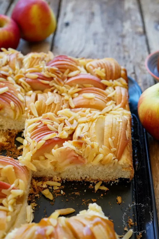 Ein Stück Butterkuchen mit Äpfeln und Karamellsoße auf einem Teller, daneben eine Kugel Eis