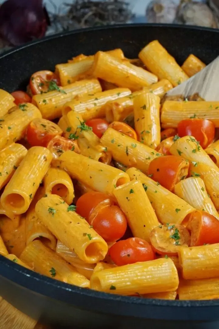 Ein Teller cremiger Pasta mit Tomaten-Mascarpone-Sauce, garniert mit frischen Kräutern, bereit zum Genießen.