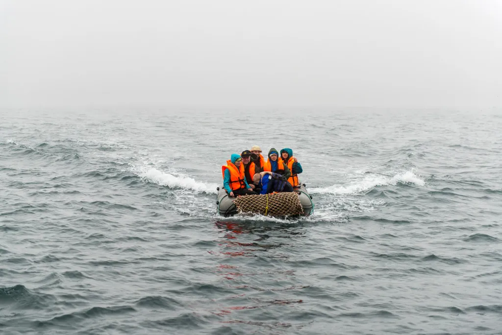 Ein unberührter See spiegelt die umgebende hügelige Landschaft mit bewaldeten Ufern wider, unter einem weiten, klaren Himmel.