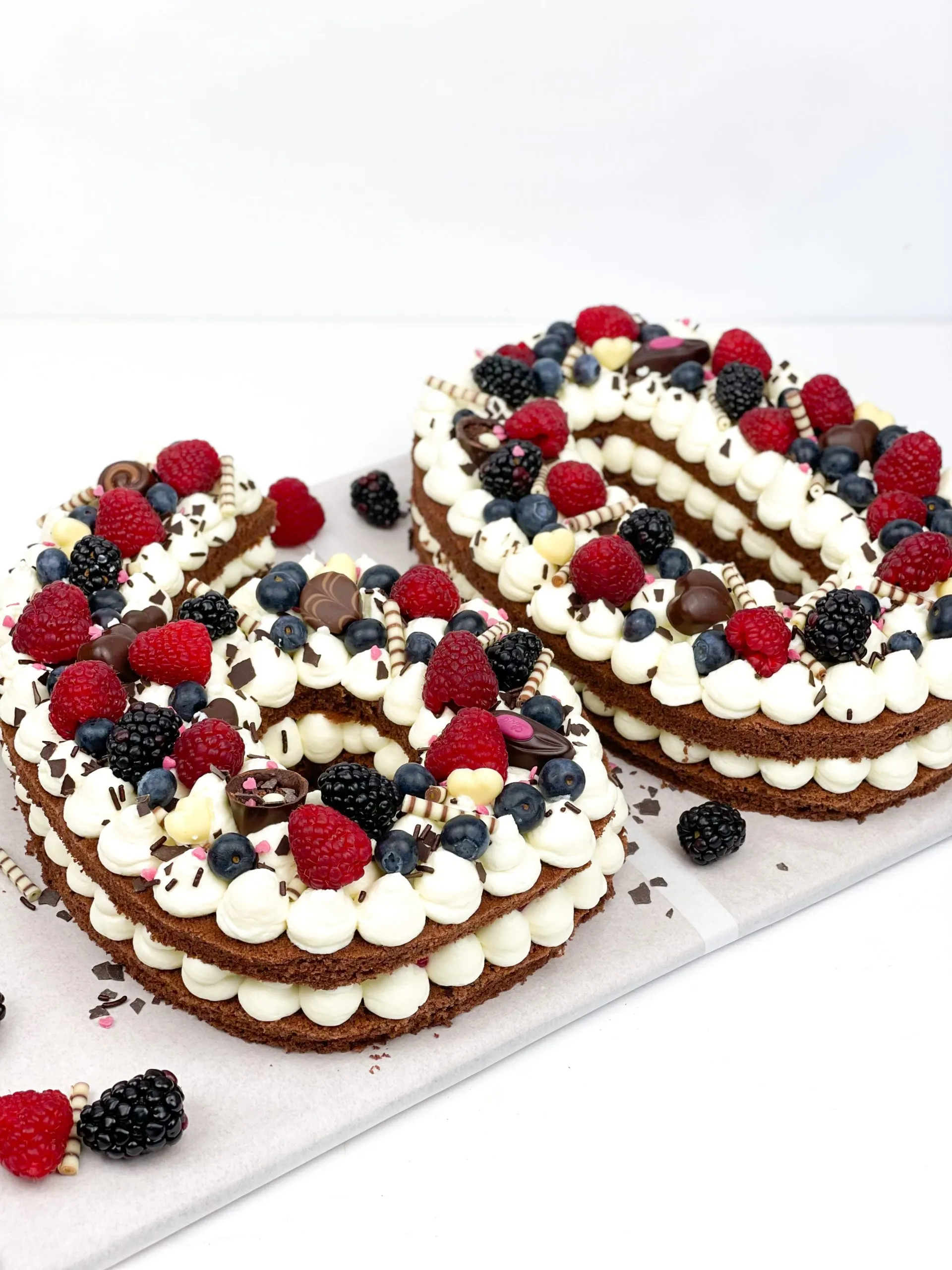 Ein wunderschön verzierter Number Cake in Form der Zahl 60 mit frischen Beeren und Schokolade