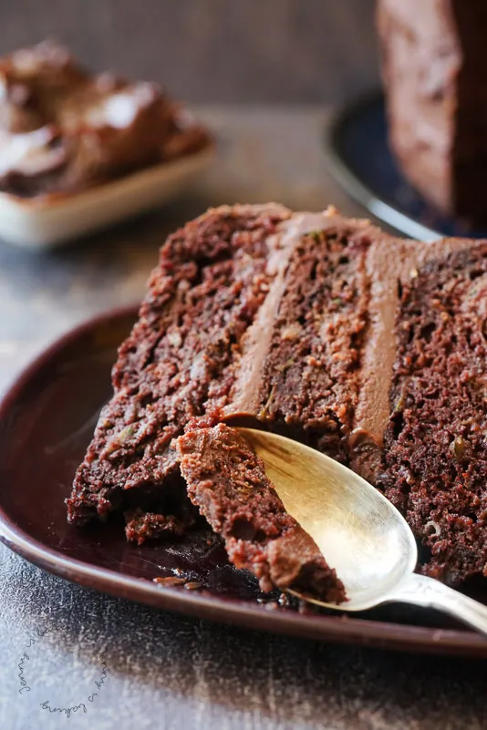 Eine appetitliche Nahaufnahme eines Stücks Schoko-Zucchini-Torte, umrahmt von frischen Himbeeren.