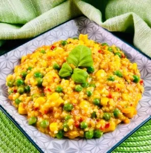 Eine dampfende Schüssel Hirsotto, goldgelb gefärbt, appetitlich angerichtet