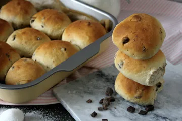 Eine dampfende Tasse Kaffee neben frischen Hefebrötchen, perfekt für ein deutsches Frühstück.