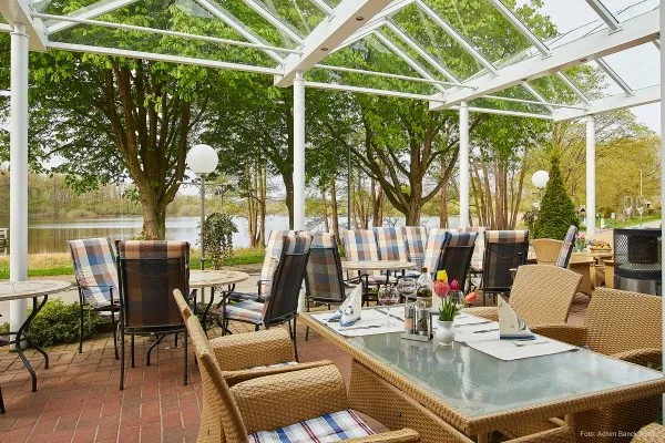 Eine einladende Restaurantterrasse mit direktem Seeblick und Gästen beim Speisen