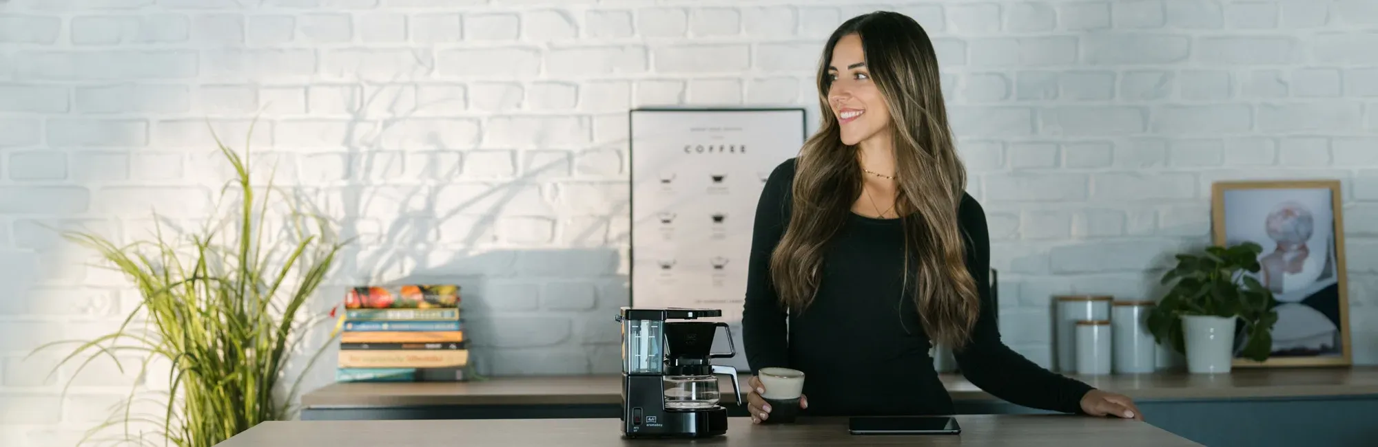 Eine Frau genießt ihren frisch gebrühten Filterkaffee aus der Melitta Aromaboy® in einer gemütlichen Umgebung