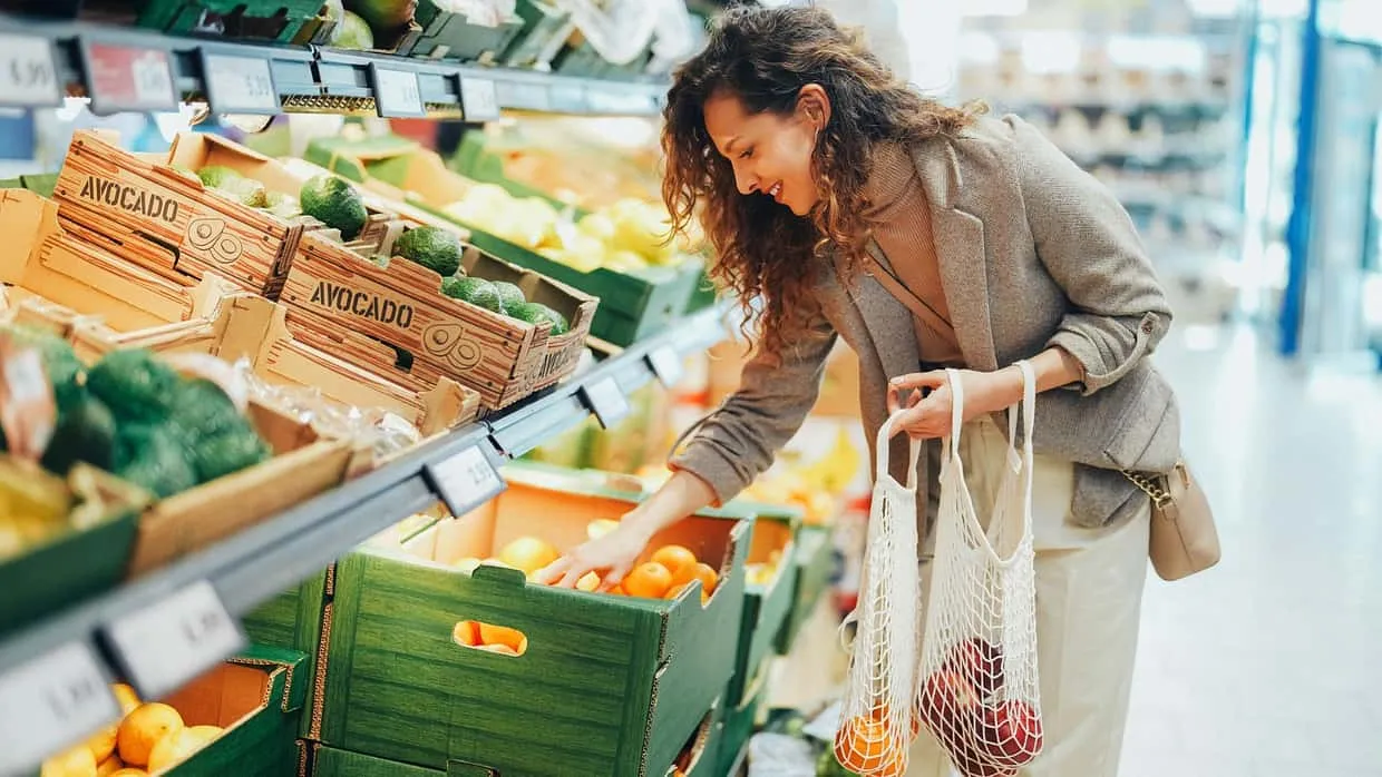 Eine Frau wählt im Supermarkt, welches Obst und Gemüse sie kauft