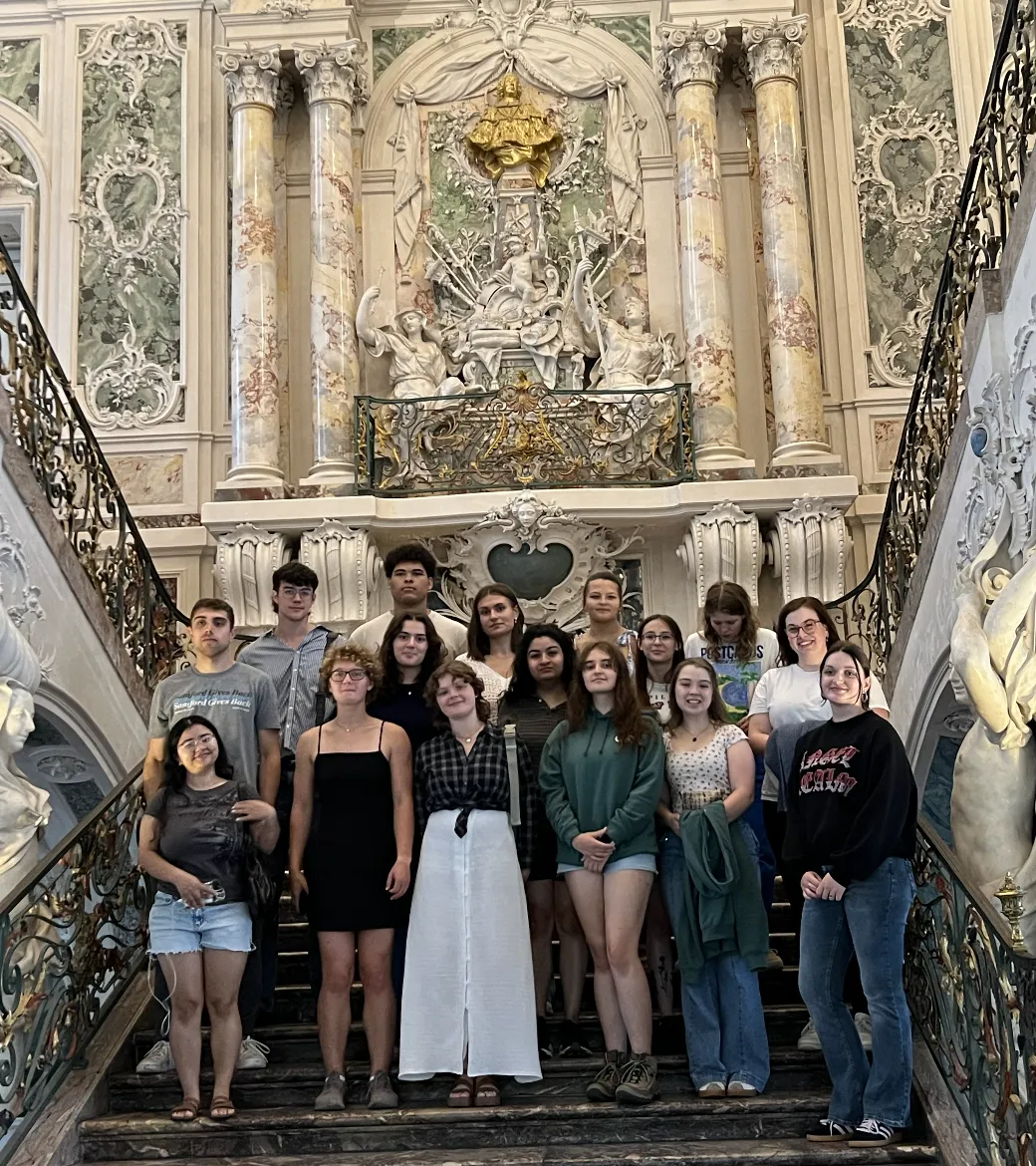 Eine Gruppe Studierender posiert lachend vor einer deutschen Stadtkulisse