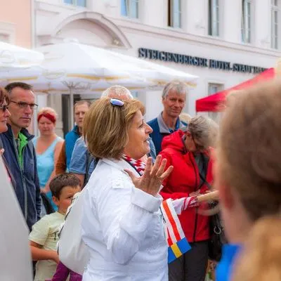 Eine Gruppe von Menschen bei einer Stadtführung in Wismar, die auf ein historisches Gebäude zeigt