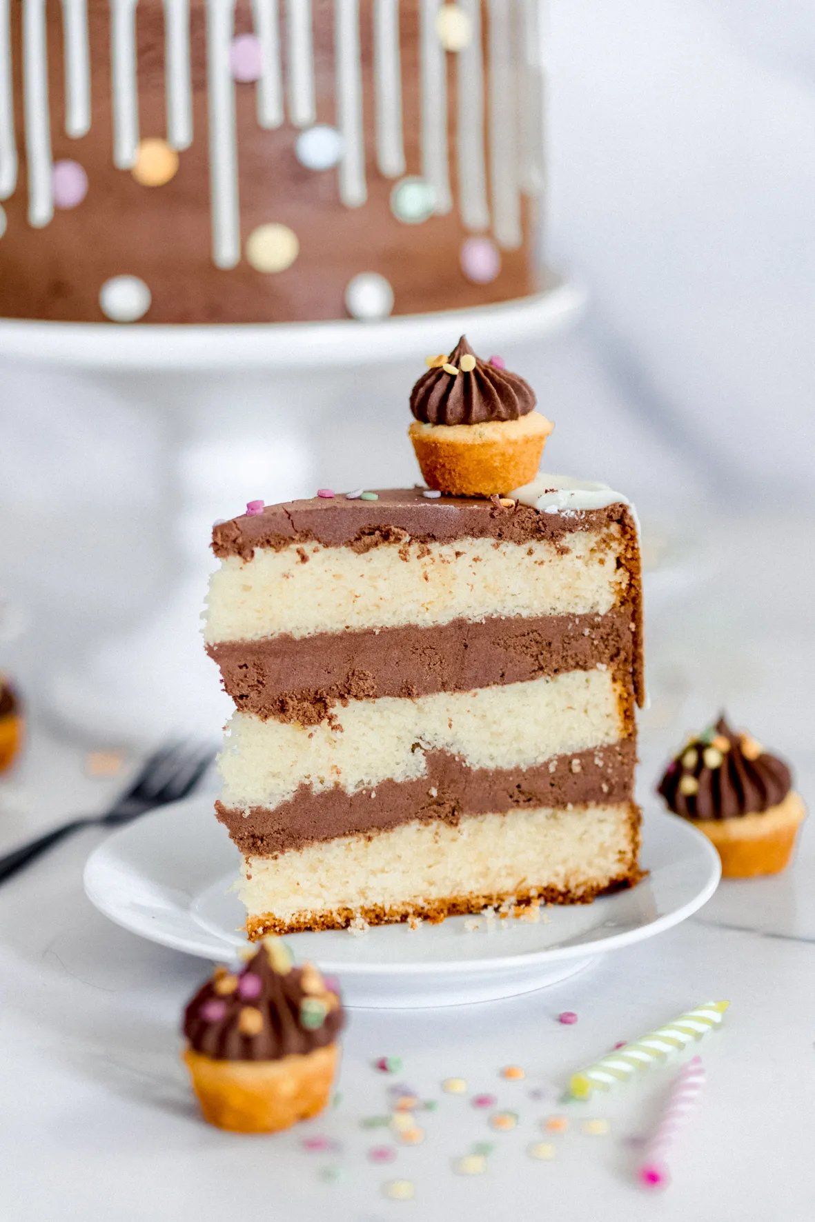 Eine Nahaufnahme der fertig dekorierten Schoko Sahne Torte mit Schokodrip, Mini-Muffins und bunten Streuseln