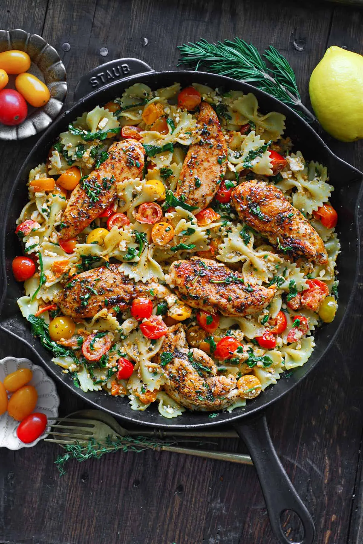 Eine Nahaufnahme von perfekt gegarter Feta-Pasta mit Hähnchen, Schleifchennudeln und frischem Gemüse, servierfertig in einer Pfanne.