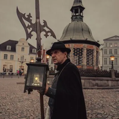 Eine Person in mittelalterlicher Nachtwächterkleidung hält eine Laterne in den Händen