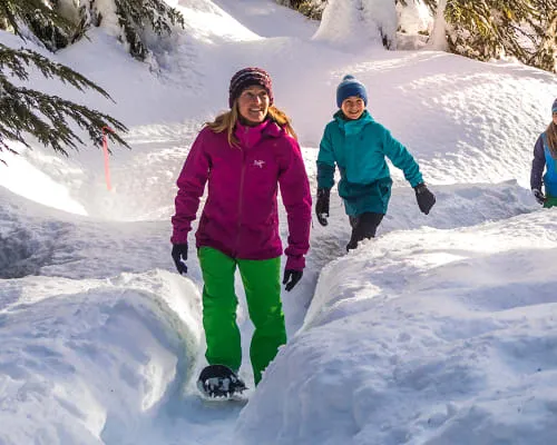 Eine Person wandert mit Schneeschuhen durch einen tief verschneiten Wald