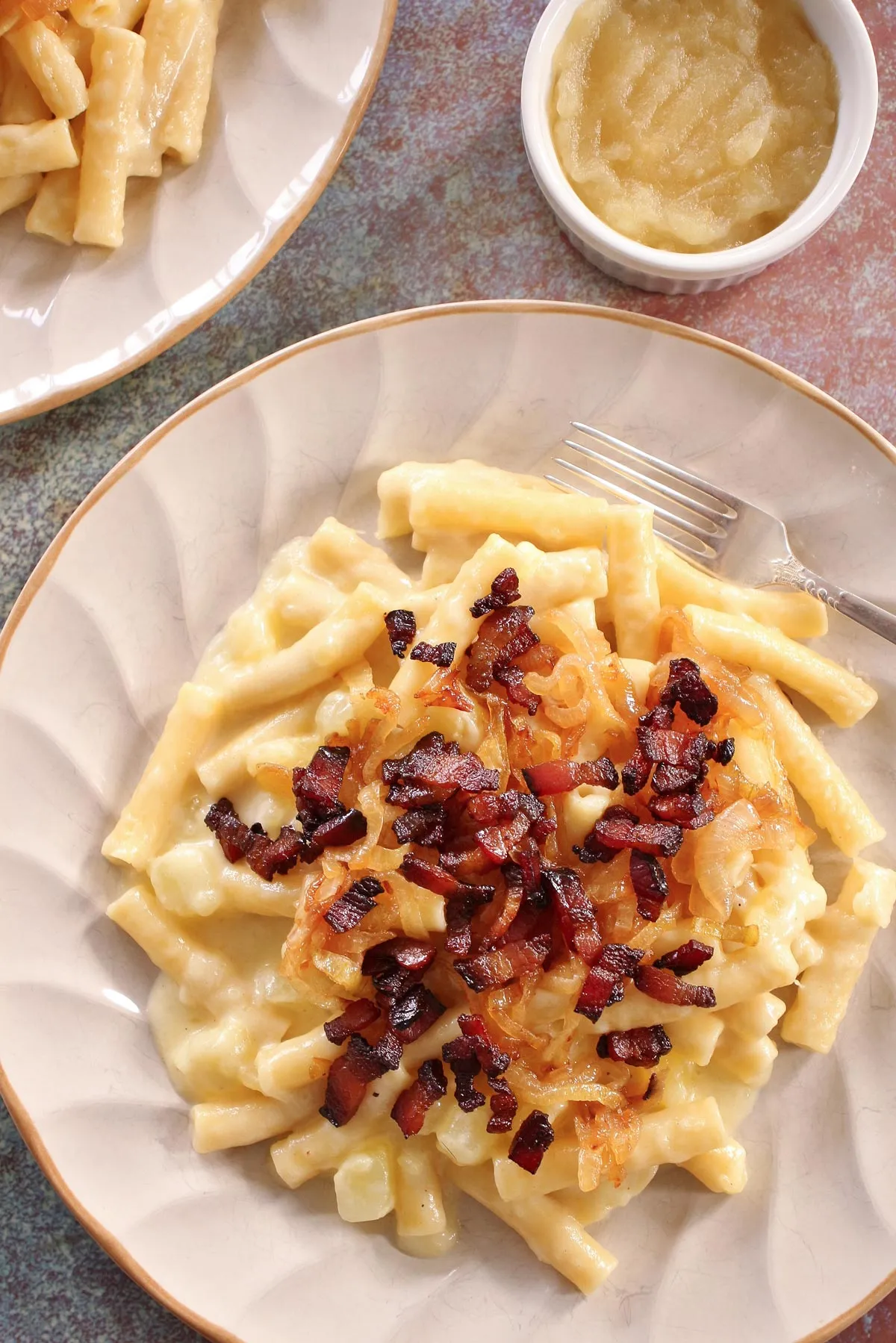 Eine Platte Schweizer Älplermagronen mit Speck und einer Beilage Apfelmus