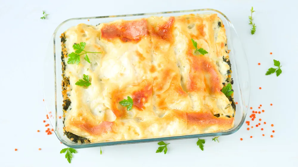 Eine vegetarische Linsen-Lasagne mit Spinat, frisch aus dem Ofen, in einer Auflaufform