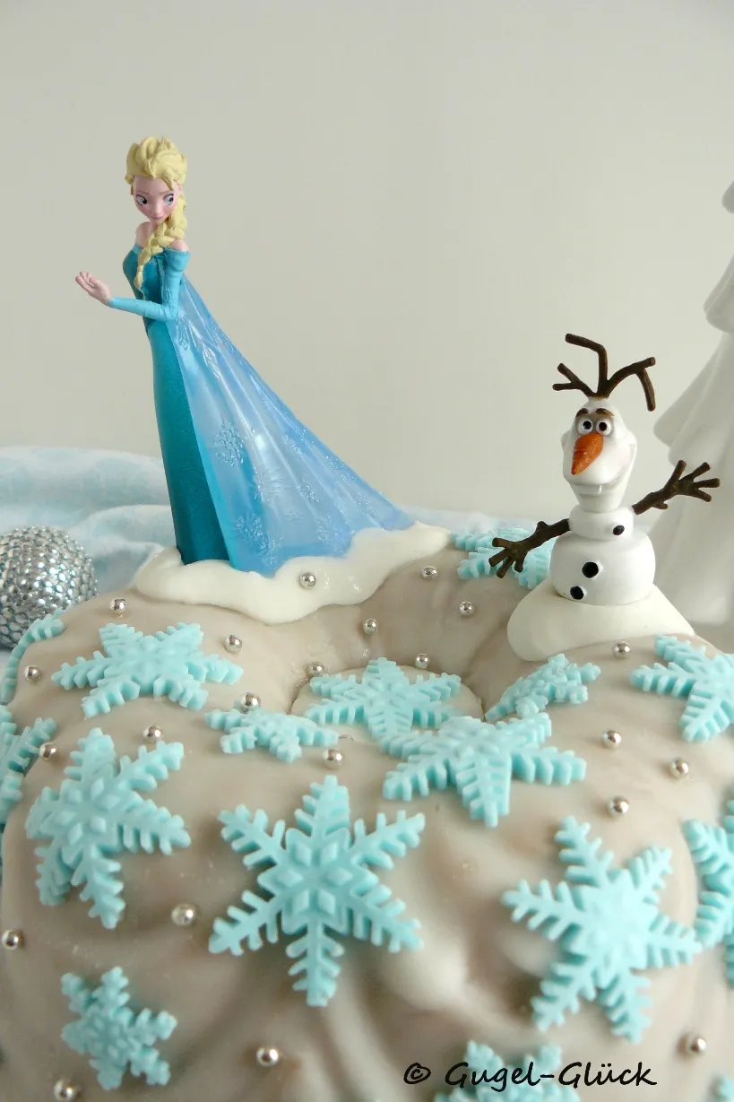 Elsa und Olaf Figuren auf einem dekorierten Kuchen.