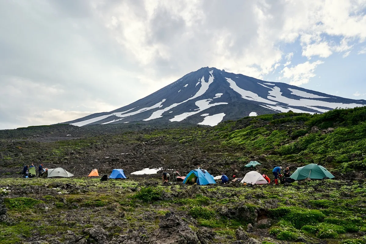 Expeditionscamp mit Zelten vor dem Kambalny Vulkan bei Einbruch der Dunkelheit
