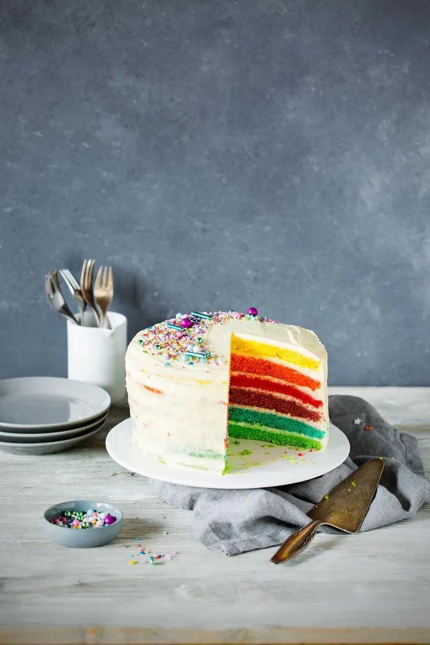 Farbenfroher Regenbogenkuchen mit cremigem Cheesecake-Frosting, ein Highlight auf jeder Kita-Feier.