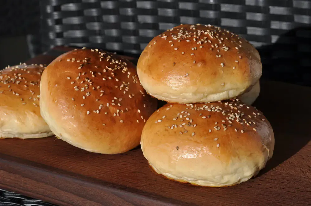 Fertige, goldbraun gebackene Hamburger Brötchen kühlen auf einem Gitterrost aus