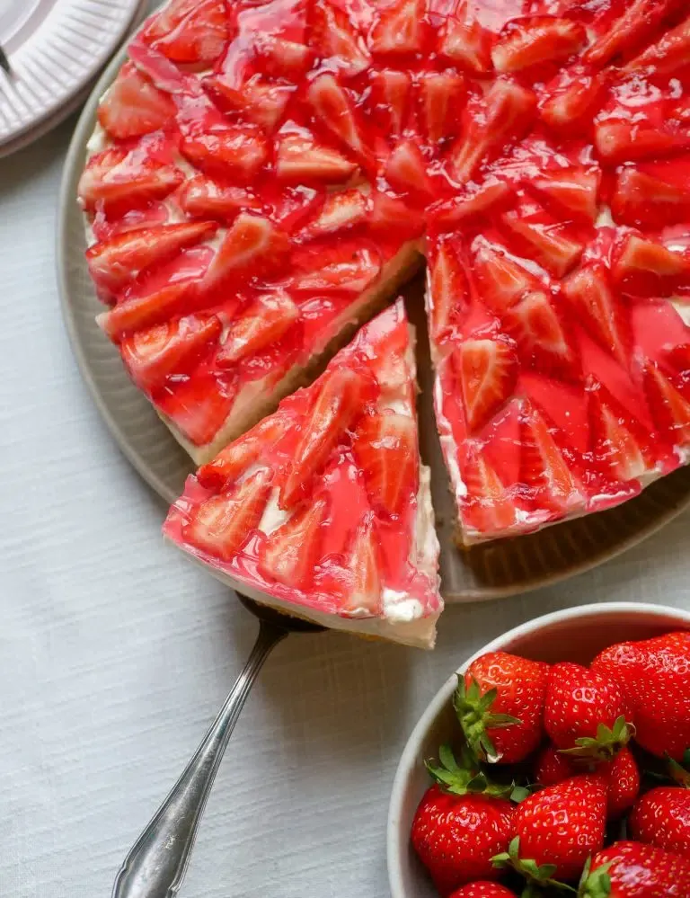 Fertiger Erdbeerkuchen mit Erdbeeren und Tortenguss, leicht verschwommen im Hintergrund