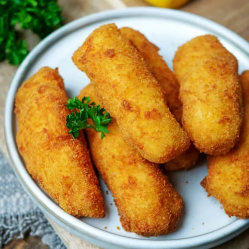 Frisch frittierte Kroketten werden mit einer Schaumkelle aus dem Öl gehoben und auf Küchenpapier zum Abtropfen gelegt.