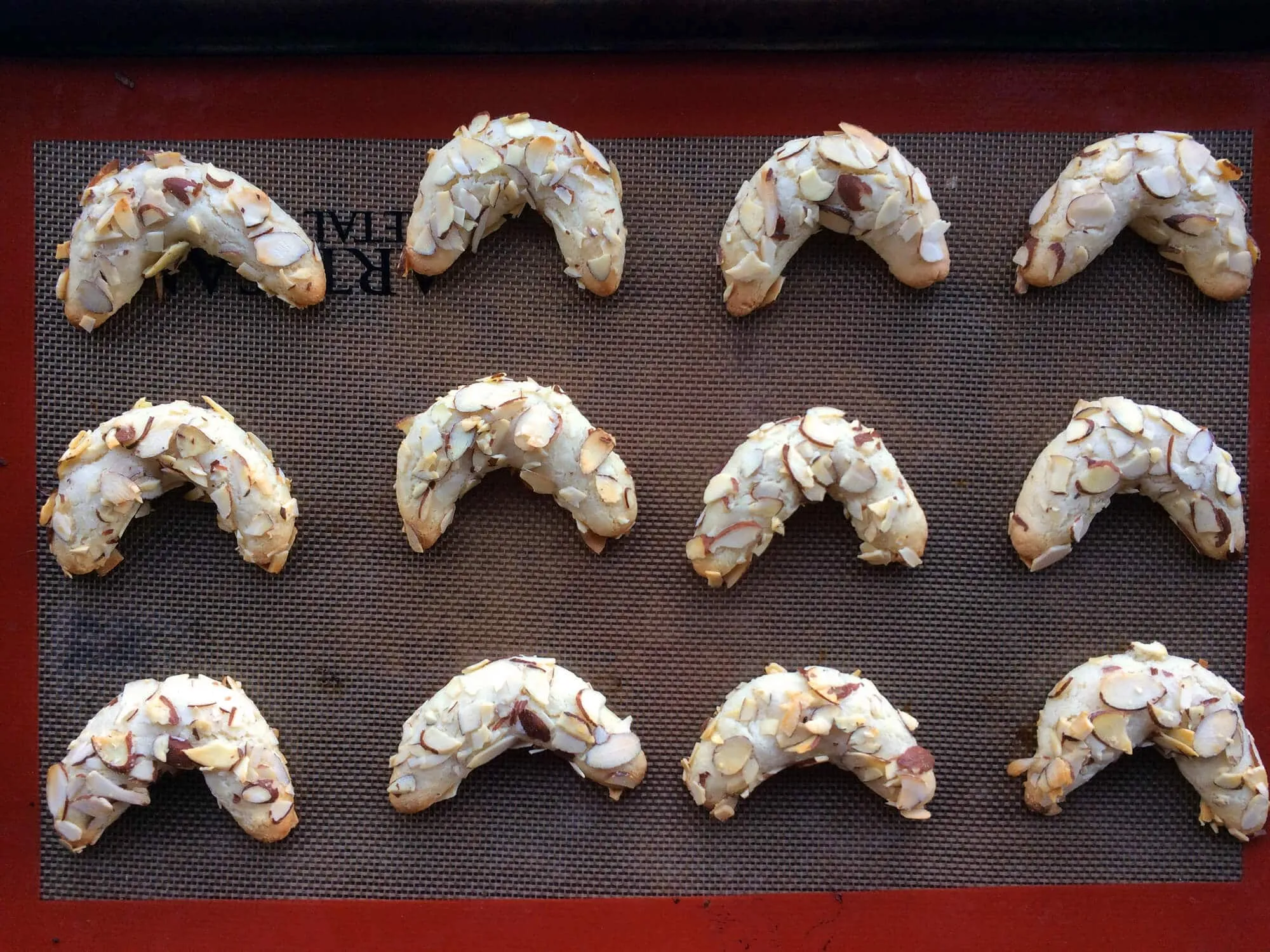 Frisch gebackene Mandelhörnchen auf einem Kuchengitter zum Abkühlen