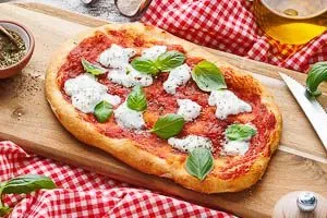 Frisch gebackene Pinsa garnieren und servieren