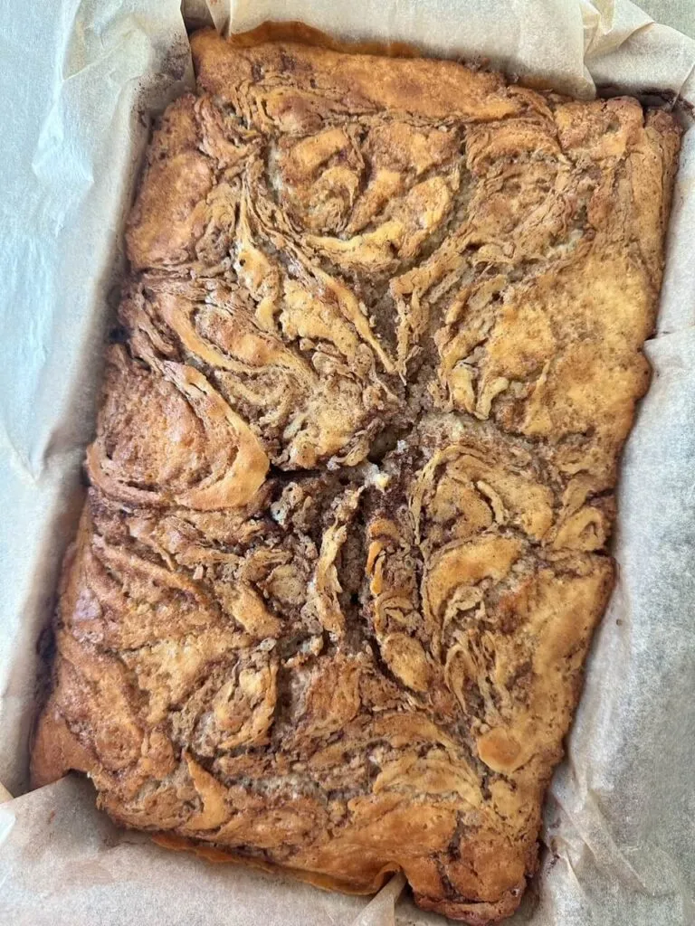 Frisch gebackener Zimtschnecken Kuchen direkt aus dem Ofen, mit sichtbarer Zimtfüllung, bereit für die Glasur