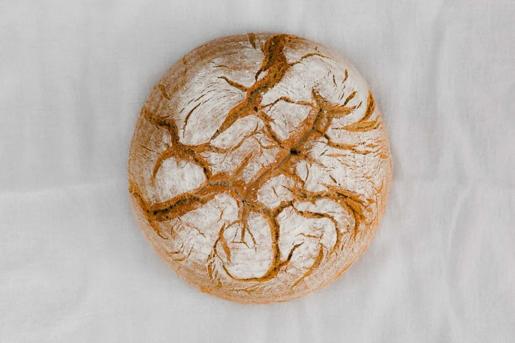 Frisch gebackenes veganes Schweizer Bauernbrot auf einem Holzbrett, knusprig geschnitten und bereit zum Genuss.