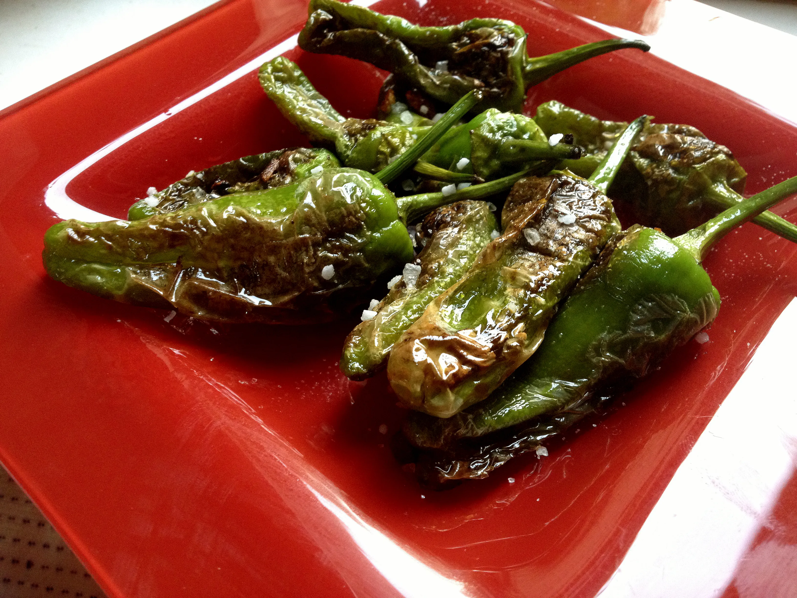 Frisch gebratene grüne Pimientos de Padrón mit grobem Meersalz in einer Pfanne