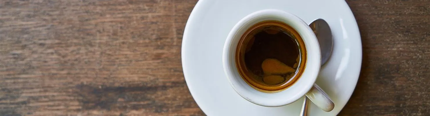 Frisch zubereiteter Espresso fließt aus der Siebträgermaschine in eine Espressotasse mit goldbrauner Crema