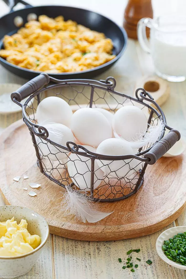 Frische Eier, Milch, Butter und Kräuter als Basis für Rührei