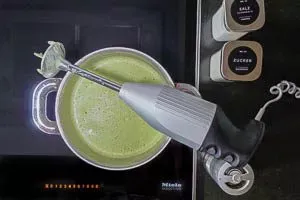 Frischer Bärlauch wird zur Suppe gegeben und mit einem Pürierstab cremig gemixt