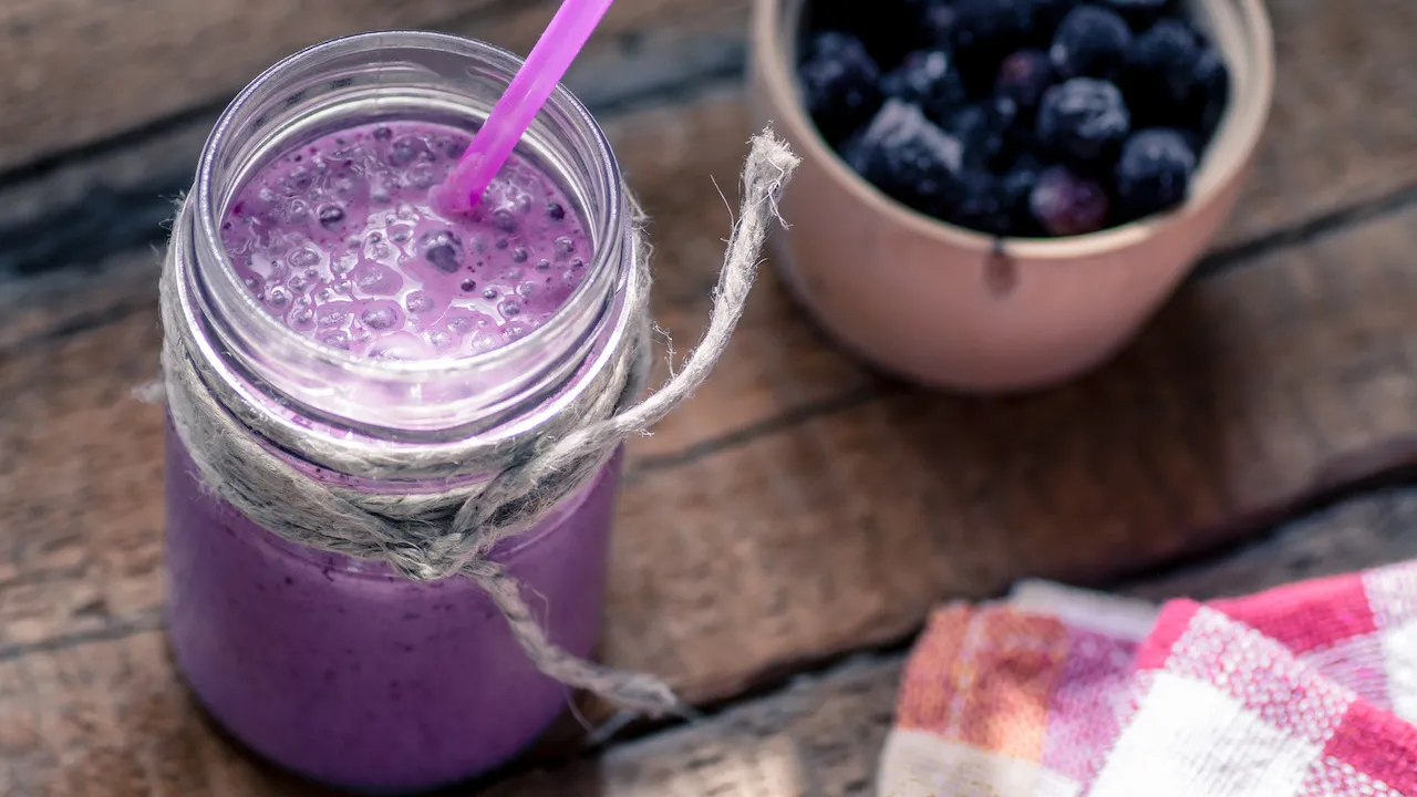 Fruchtiger Frozen Berry Joghurt-Smoothie in einem Glas, garniert mit frischen Beeren