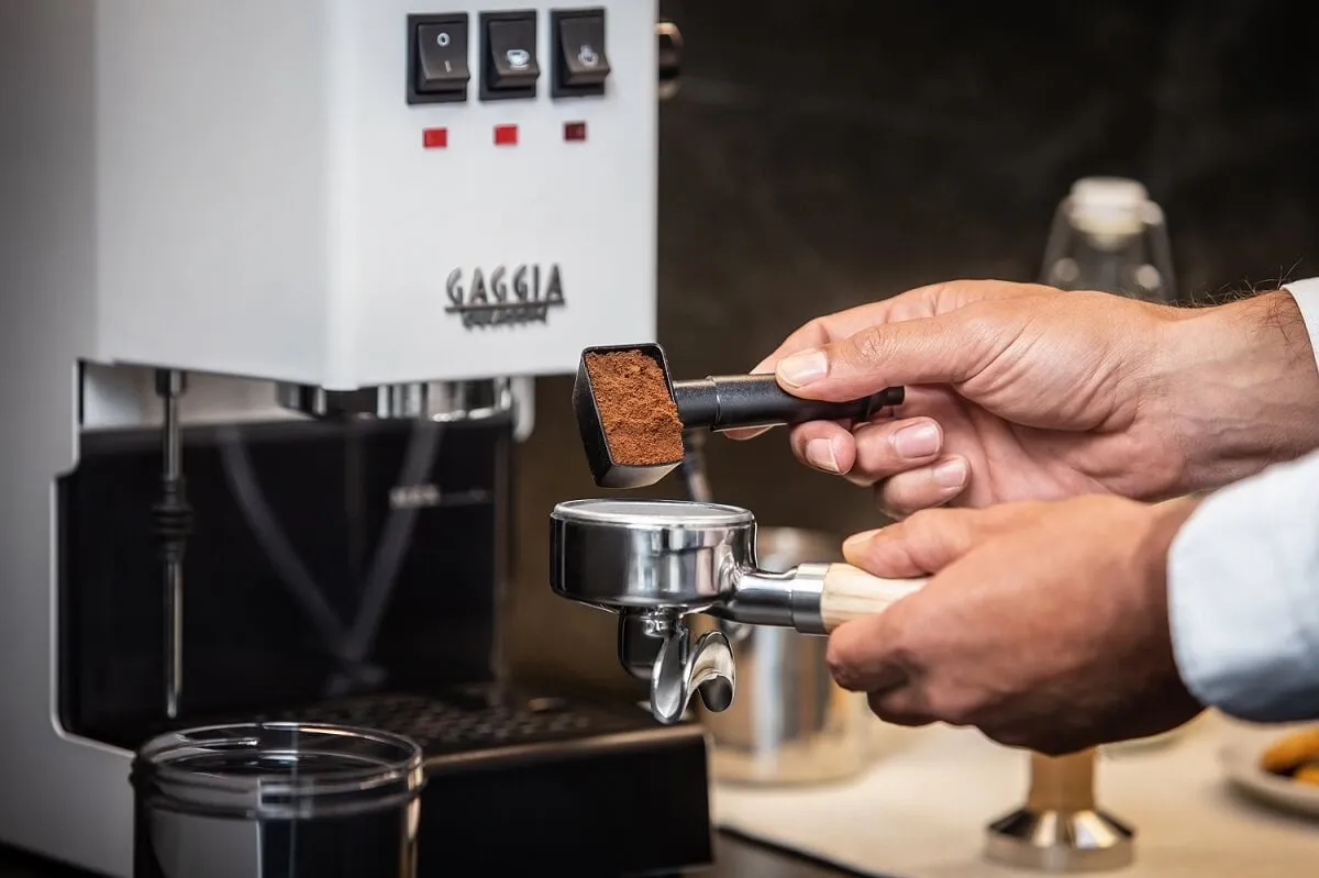 Gaggia New Classic Siebträgermaschine mit Hand, die Siebträger mit Kaffeepulver füllt