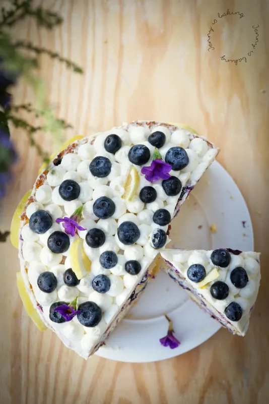 Ganze Heidelbeer-Zitronen-Torte von oben, dekoriert mit frischen Beeren und Zitronenscheiben, ideal für den Geburtstag