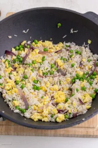 Gebratener Reis wird in einem Wok zubereitet, viele Zutaten mischen sich.