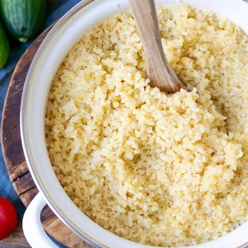 Gekochter Bulgur in einem Topf mit Holzkochlöffel.
