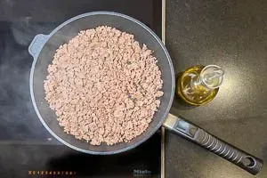 Gemischtes Hackfleisch wird in einer großen Pfanne mit Olivenöl krümelig angebraten, Basis für den herzhaften Kritharaki-Auflauf