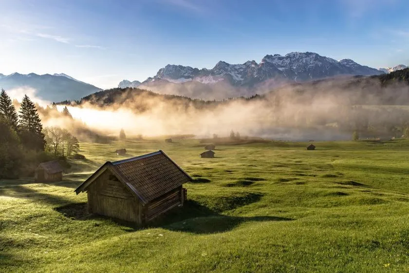 Geroldsee im Allgäu mit Morgennebel und Bergen im Hintergrund.