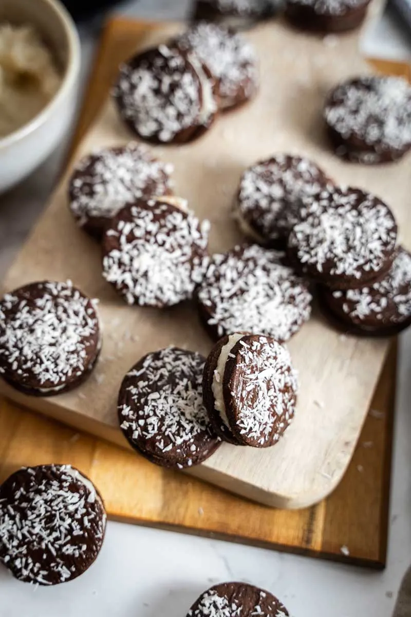 Geschichtete Kokos-Schoko-Plätzchen mit dunklem Guss und Kokosraspeln, auf einem Teller angerichtet