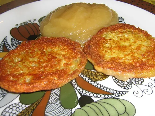 Goldbraun gebackene Kartoffelpuffer serviert mit einer Schale Apfelkompott