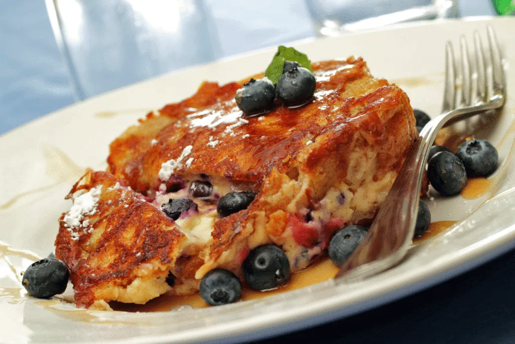 Goldbrauner French Toast mit Blaubeeren auf einem weißen Teller, serviert mit einer Gabel